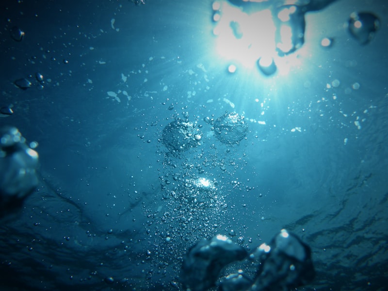 Underwater view of sunlight through clear blue water with rising air bubbles